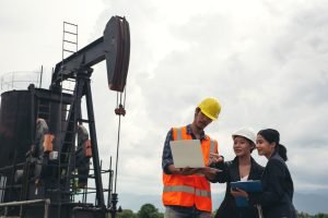 The engineering team stands beside working oil pumps with a sky