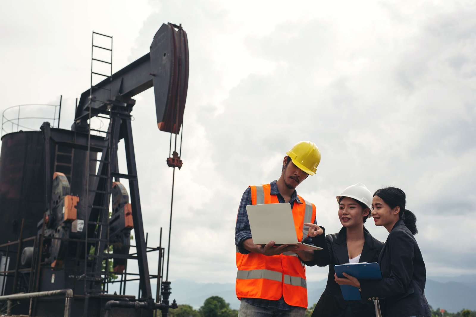 The engineering team stands beside working oil pumps with a sky