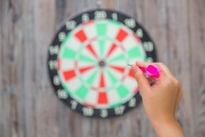 Hand holdin red arrow and throwing to dart board