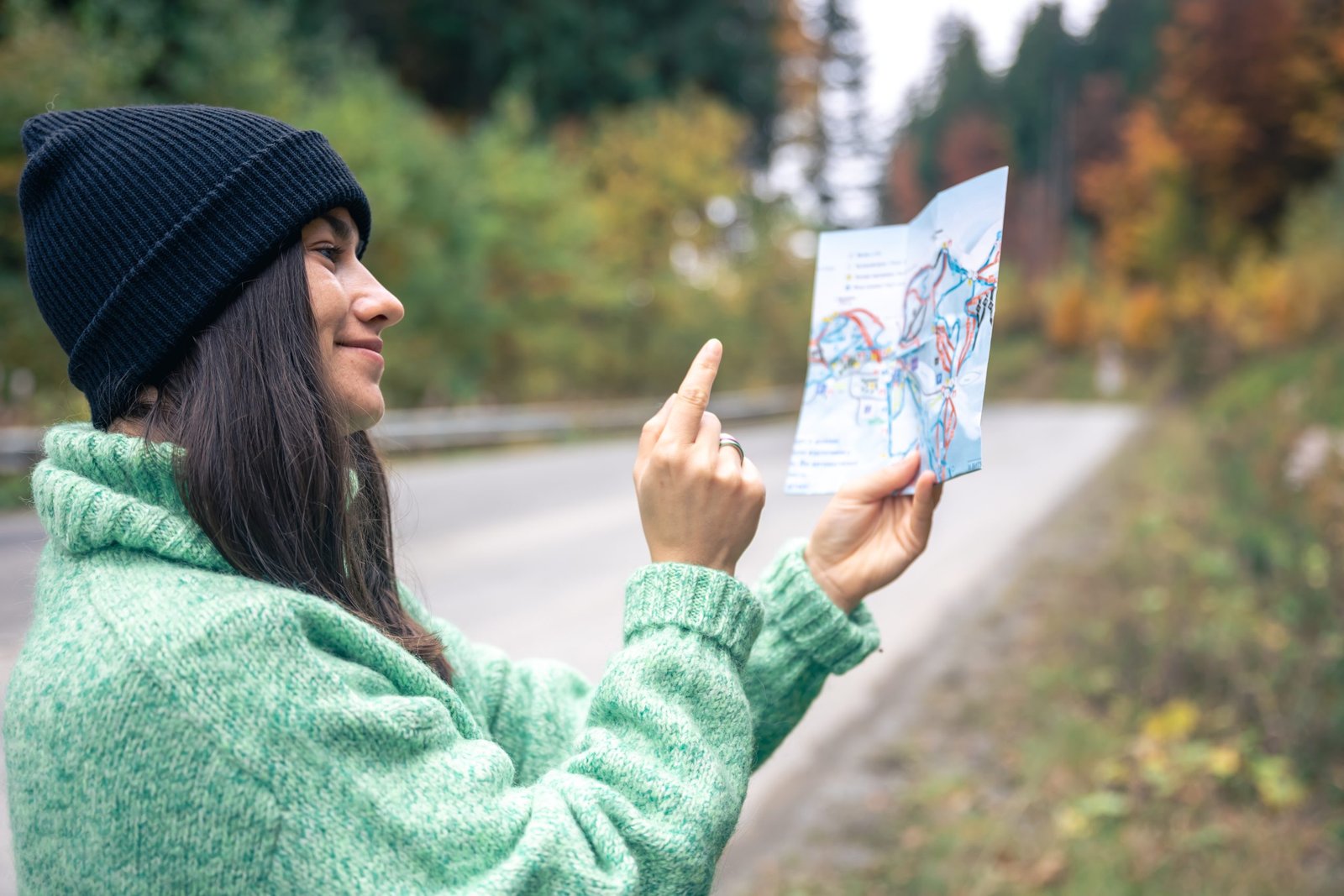 A young woman with a road map in the forest in the mountains.