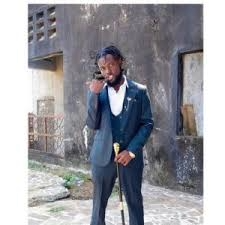El Drez, dressed in a sharp suit and holding a cane, strikes a confident pose in front of an urban backdrop. LandonBuford.com