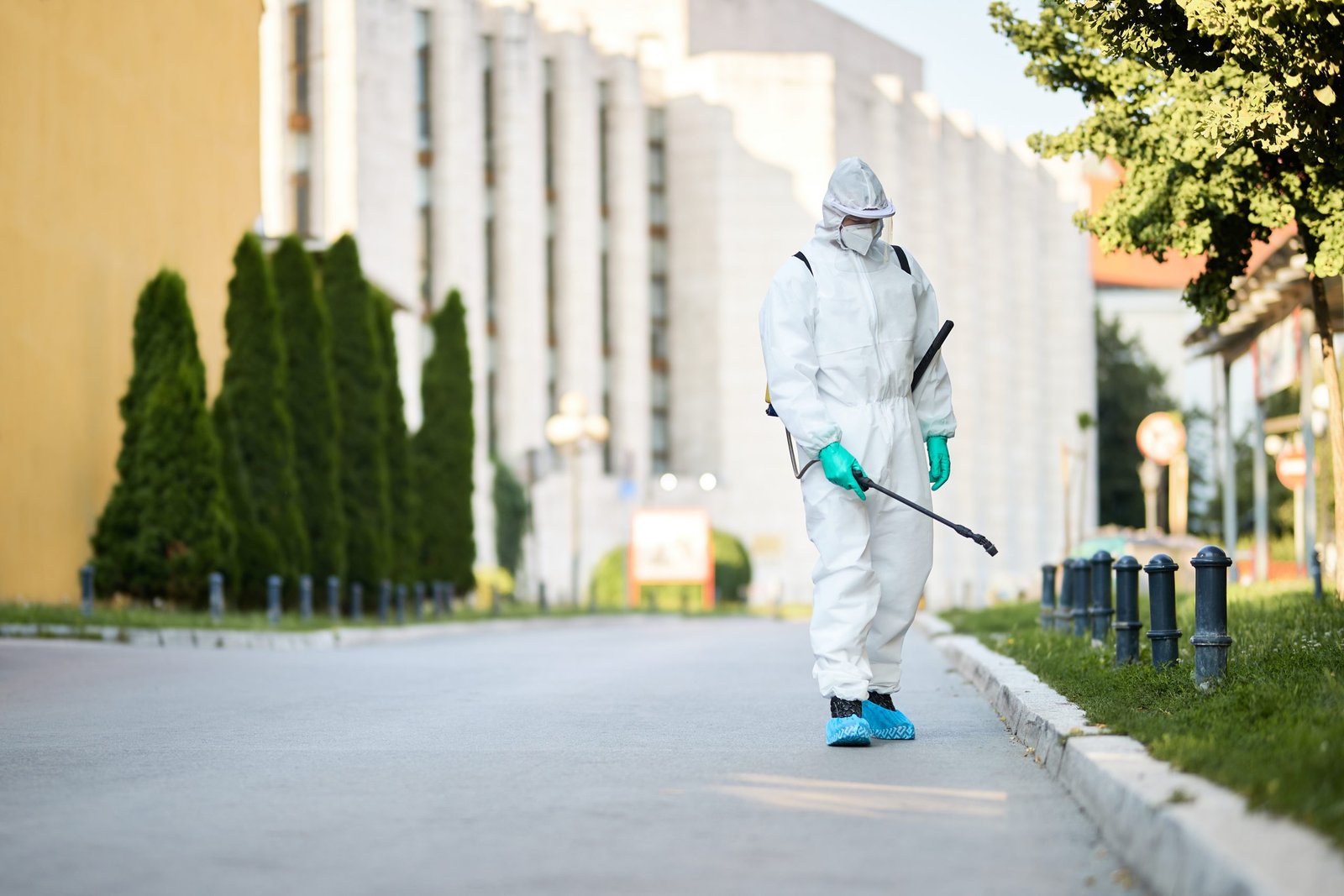 Man in a protective suit spraying disinfectant on city streets during the coronavirus pandemic. LandonBuford.com