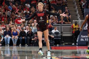 Sophie Cunningham of the Indiana Fever extends her arms during a game, wearing the team’s black and red uniform with jersey number 8. LandonBuford.com