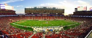 Fans using smartphones with AR apps at a modern NFL stadium with large LED screens and vibrant lighting